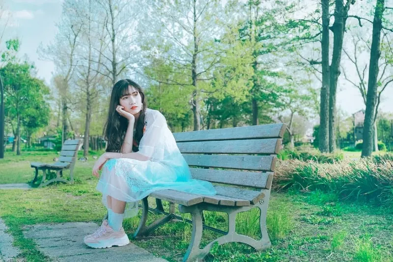 woman in white dress sitting on wooden bench