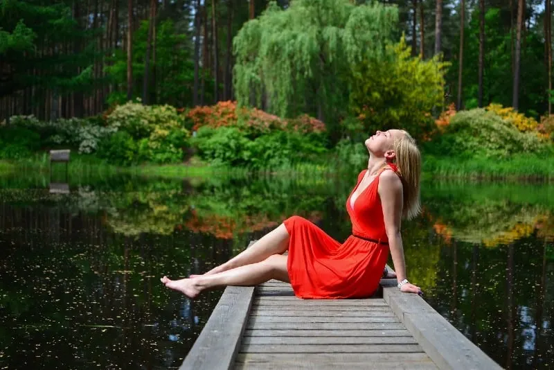 woman in red dress sitting on wooden dock