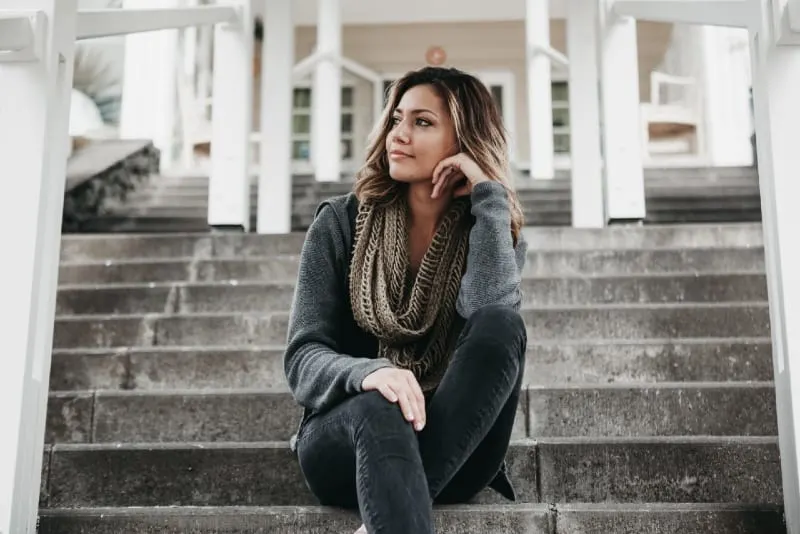 woman with gray scarf sitting on steps