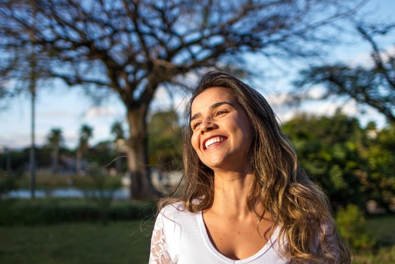 mujer con top blanco sonriendo al aire libre