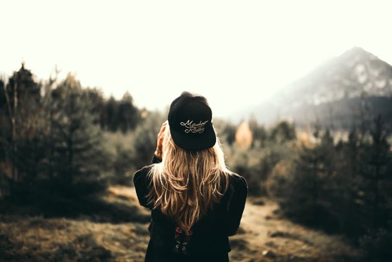 woman with black cap standing in forest