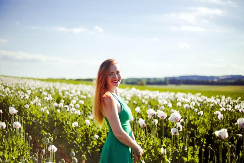 woman in green dress standing near flowers