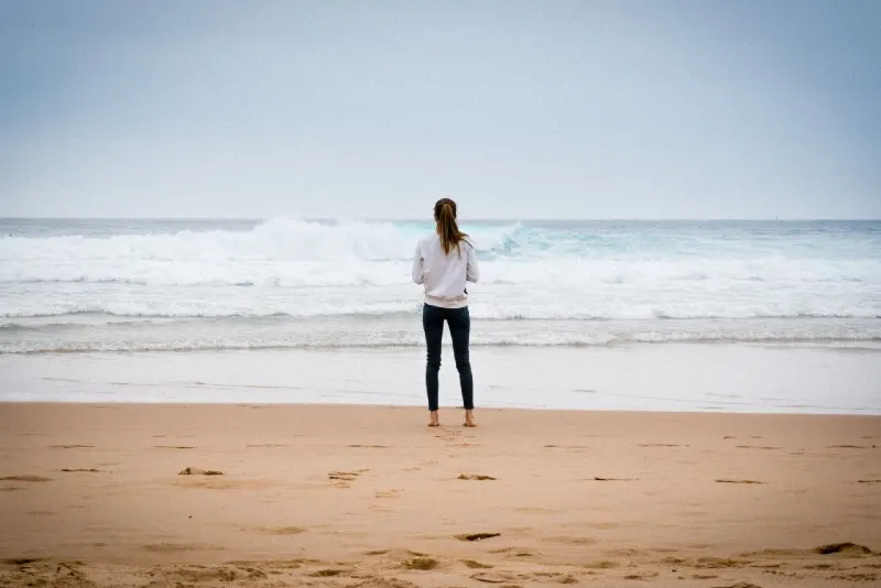 woman standing on shore looking at ocean