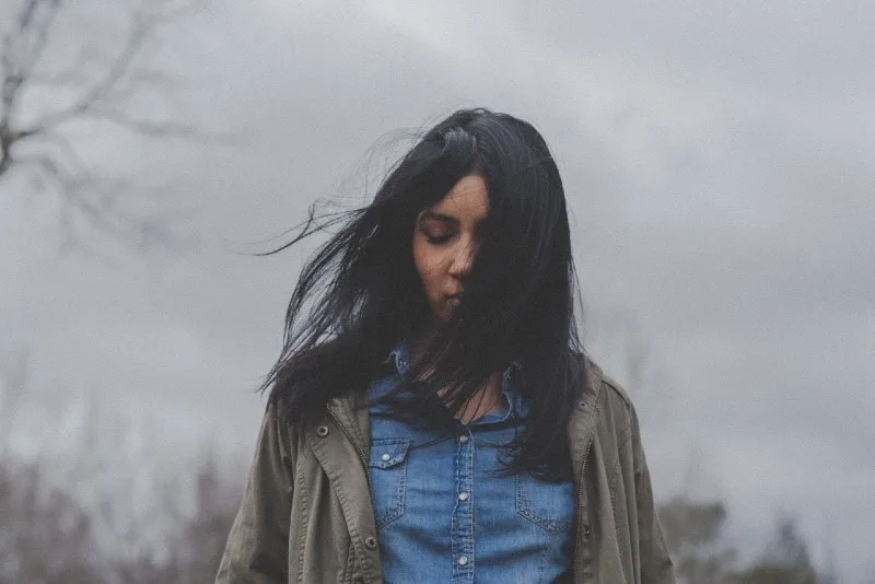 black haired woman in denim shirt standing outdoor
