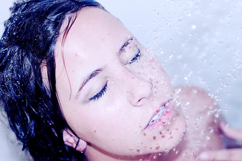 mujer duchándose con los ojos cerrados