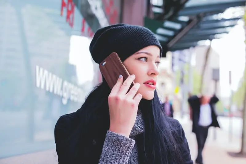 woman with black cap talking on the phone outdoor
