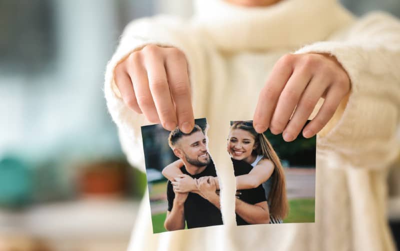 mãos de uma mulher a rasgar uma fotografia de um casal feliz