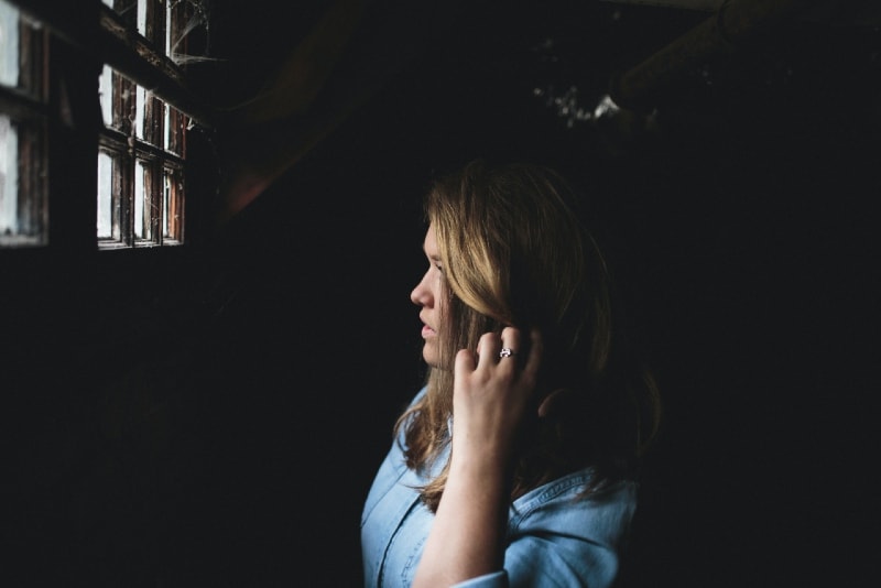 woman touching her hair while looking at the window