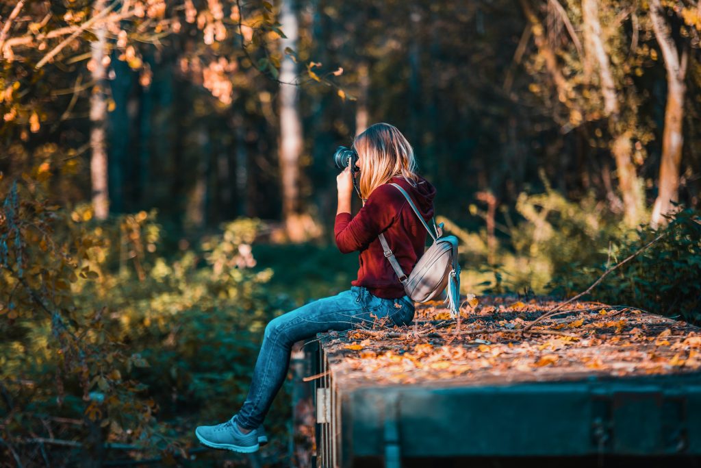 mujer usando la cámara mientras se está sentado en la naturaleza