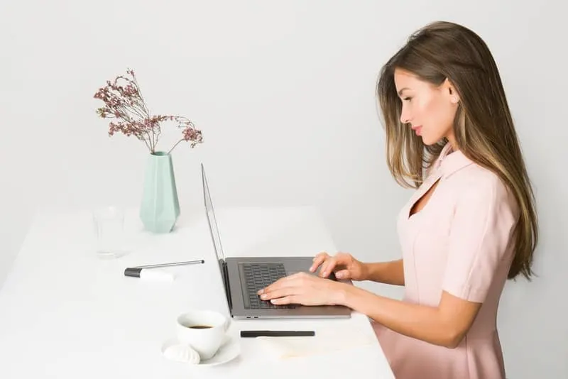 woman using laptop wearing pink dress 