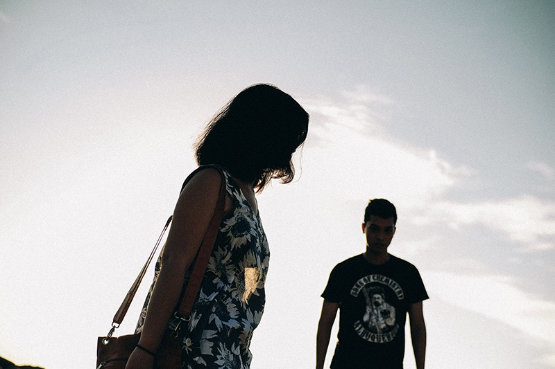 woman waiting while men is walking during daytime