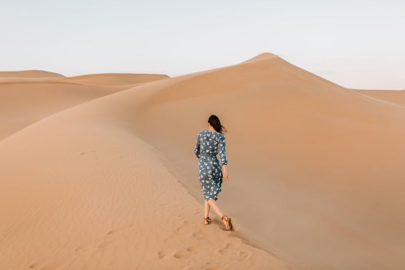 donna in abito blu stampato che cammina nel deserto