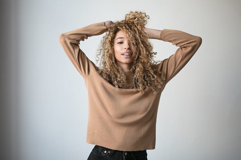 woman wearing brown sweater touching her hair