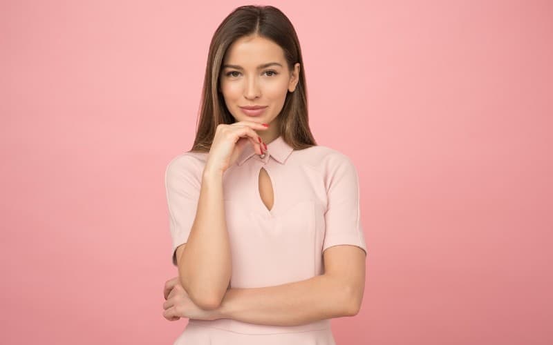 woman wearing pink top standing against pink wall