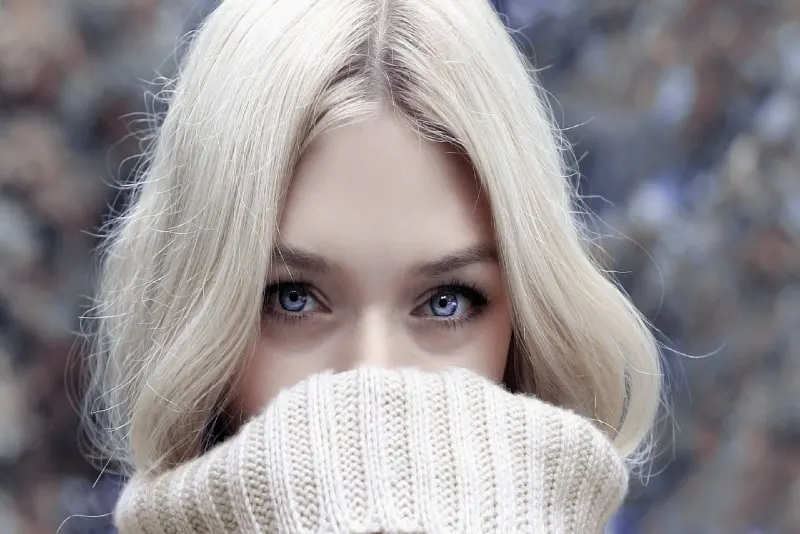 woman with blue eyes in turtleneck sweater standing outdoor