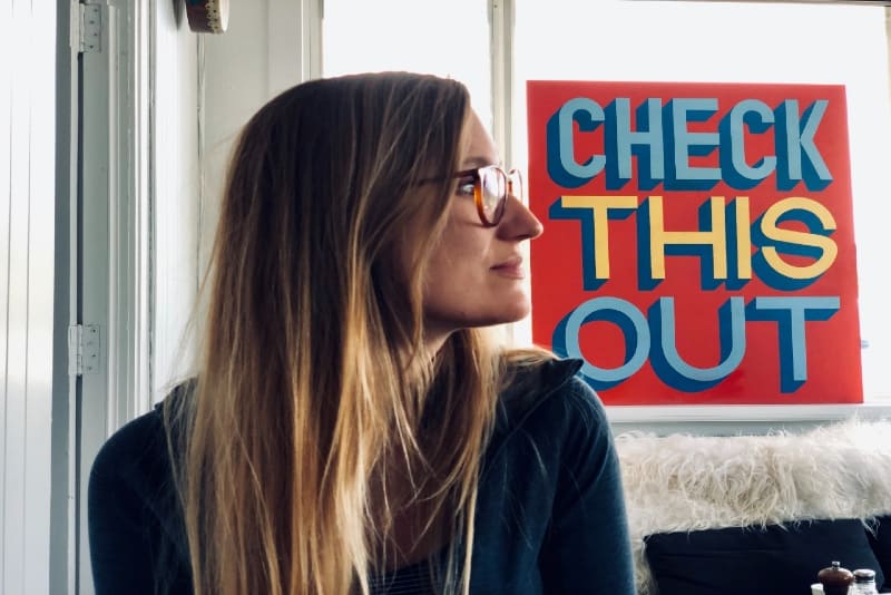 blonde woman with eyeglasses sitting indoor