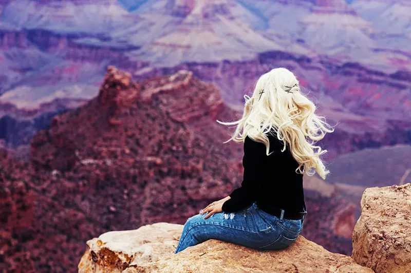woman with long blonde hair sitting on the cliff