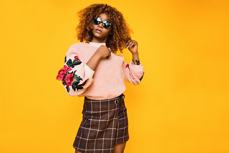 woman in pink sweatshirt and brown plaid skirt