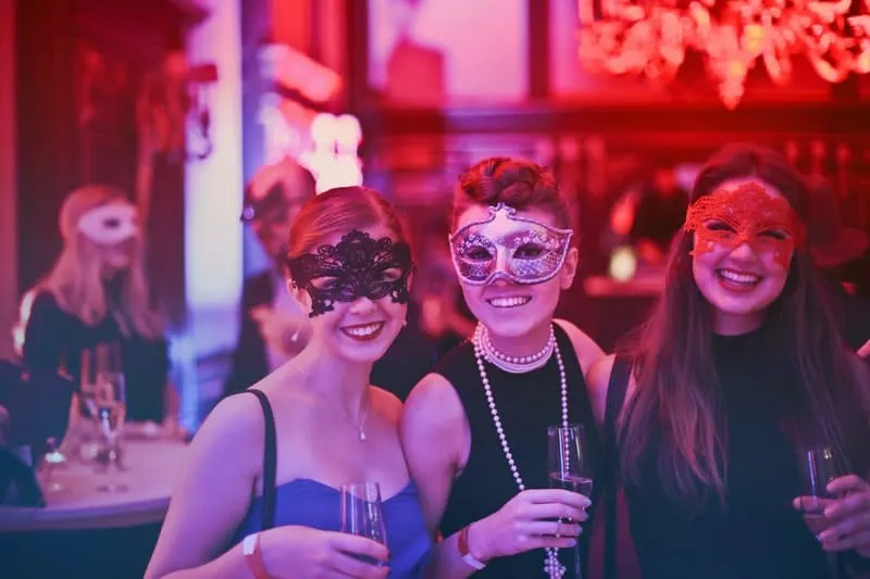 women wearing masks in a party holding wine glasses