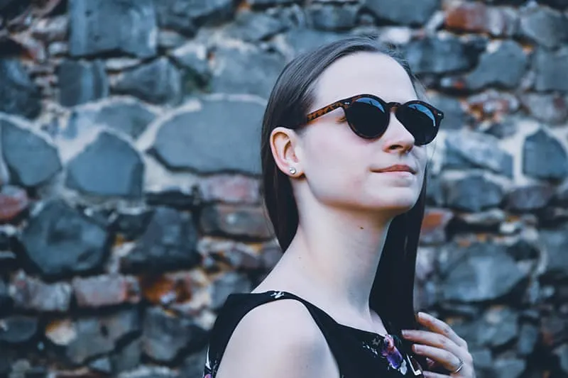 women's wearing black framed sunglasses while touching her hair