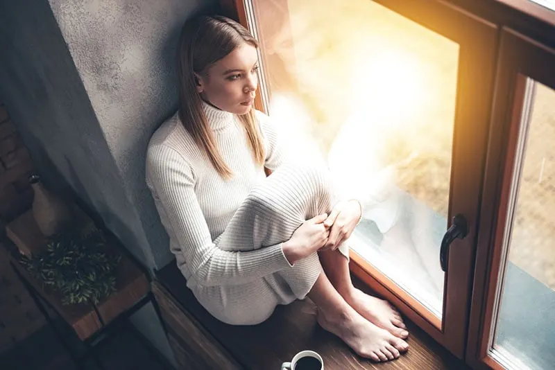 worried young woman sitting by the window