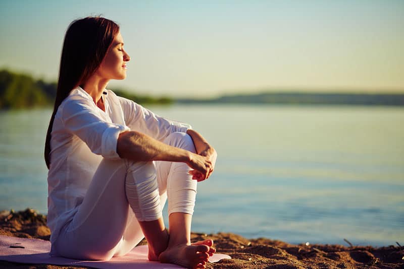 young woman meditates on the beach