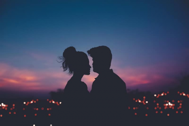 un hombre y una mujer se miran a los ojos desde un tejado