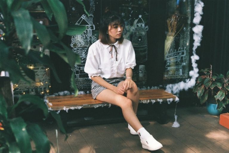 woman in white shirt sitting on brown wooden bench
