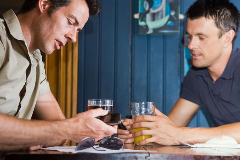2 men drinking beer while talking on a table