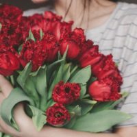 woman holding bouquet of red flowers