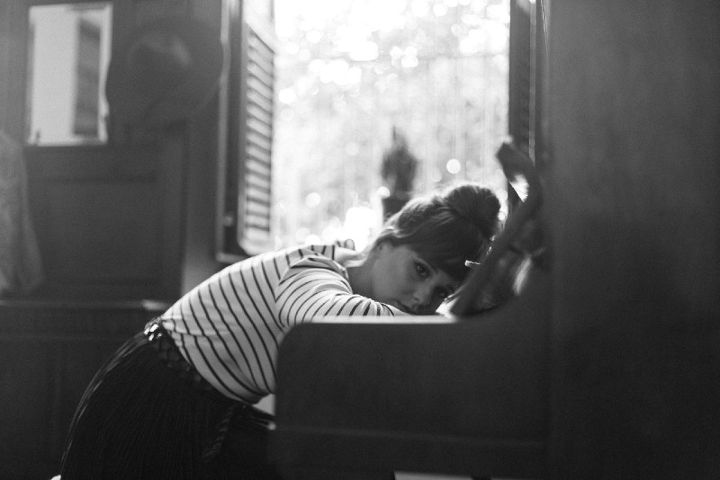 sad woman in striped top leaning on piano