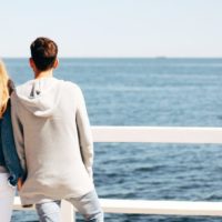 man and woman holding hands looking at sea