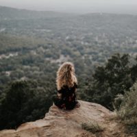 blonde woman sitting on cliff