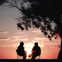 hombre y mujer sentados en sillas durante la puesta de sol