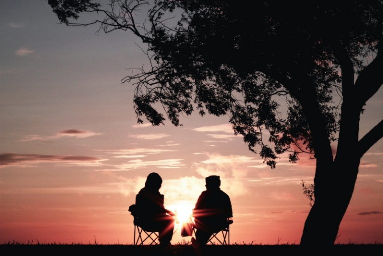 man and woman sitting on chairs during sunset