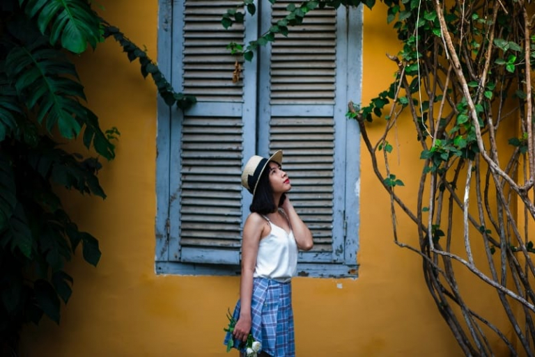 woman holding flowers while standing near window