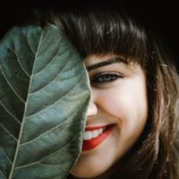 smiling woman with black hat holding leaf