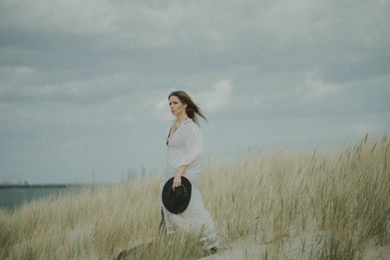 woman in white shirt holding hat while standing in field