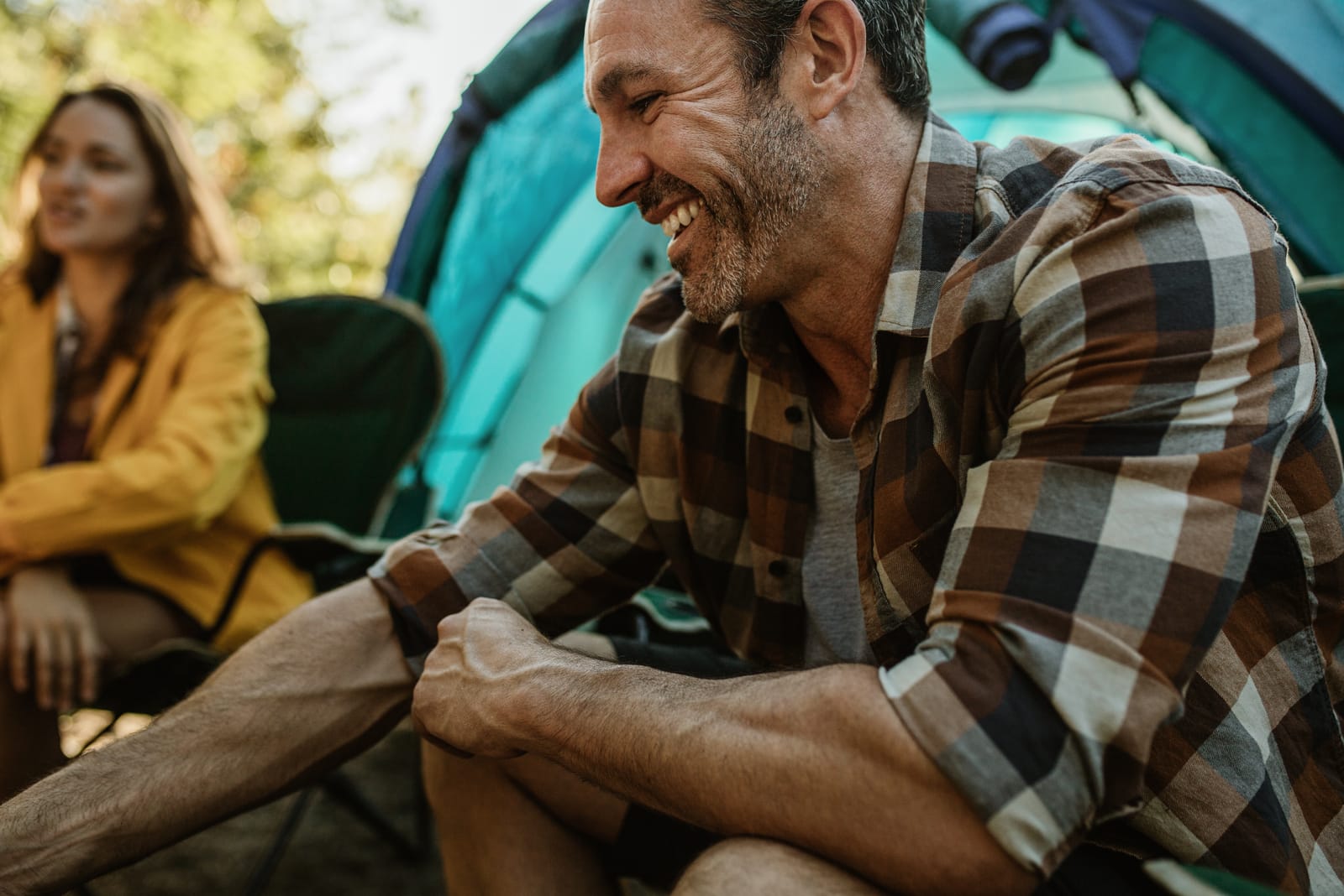 Casal em campismo sentado à porta da tenda