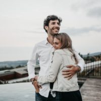 smiling man in white shirt hugging woman outdoor