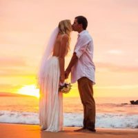 coppia di sposi che si bacia al tramonto in una bella spiaggia delle Hawaii