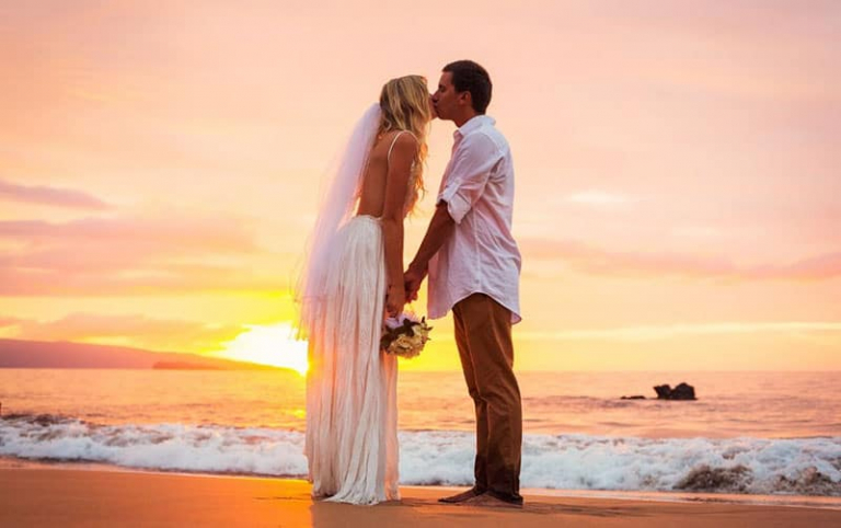 married couple kissing in the sunset in a beautiful beach of Hawaii