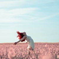 woman in yellow dress standing on pink petaled flower field