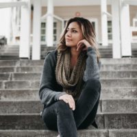 woman in gray scarf sitting on stairs