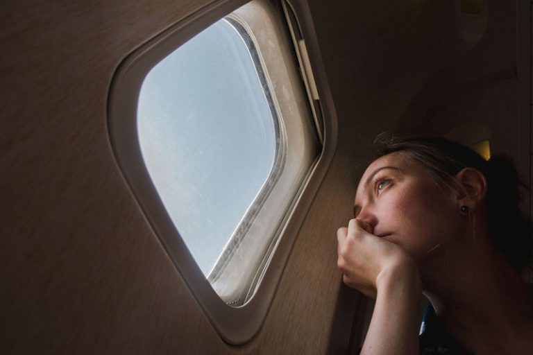 woman sitting near the window of an airplane looking outside