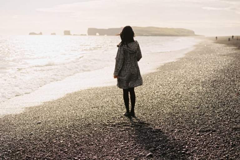 woman standing on beach looking at sea