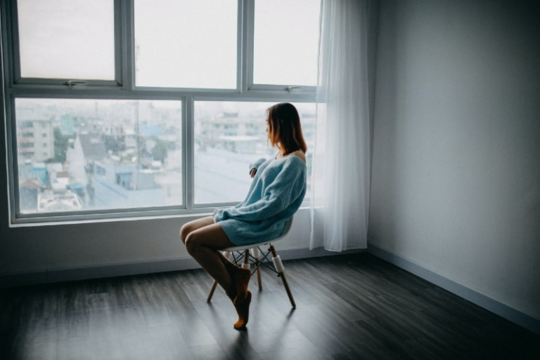 woman in blue sweater sitting on chair near window
