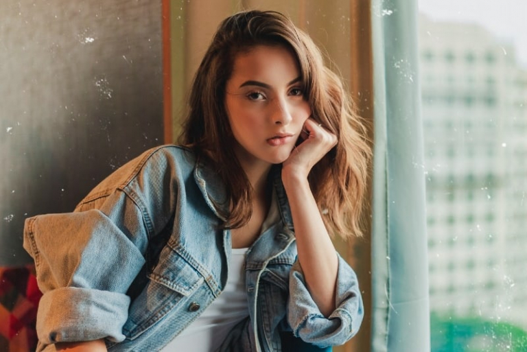 woman in denim jacket sitting with her hand on her cheek