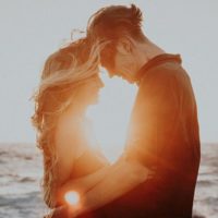 couple hugging by the beach at sunset