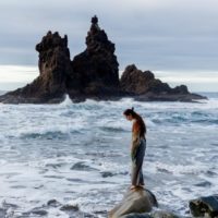 mulher de pé numa rocha perto do mar